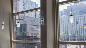 A modern bar area with large windows, metal chairs, and hanging light fixtures. - HI Chicago Hostel (Chicago)