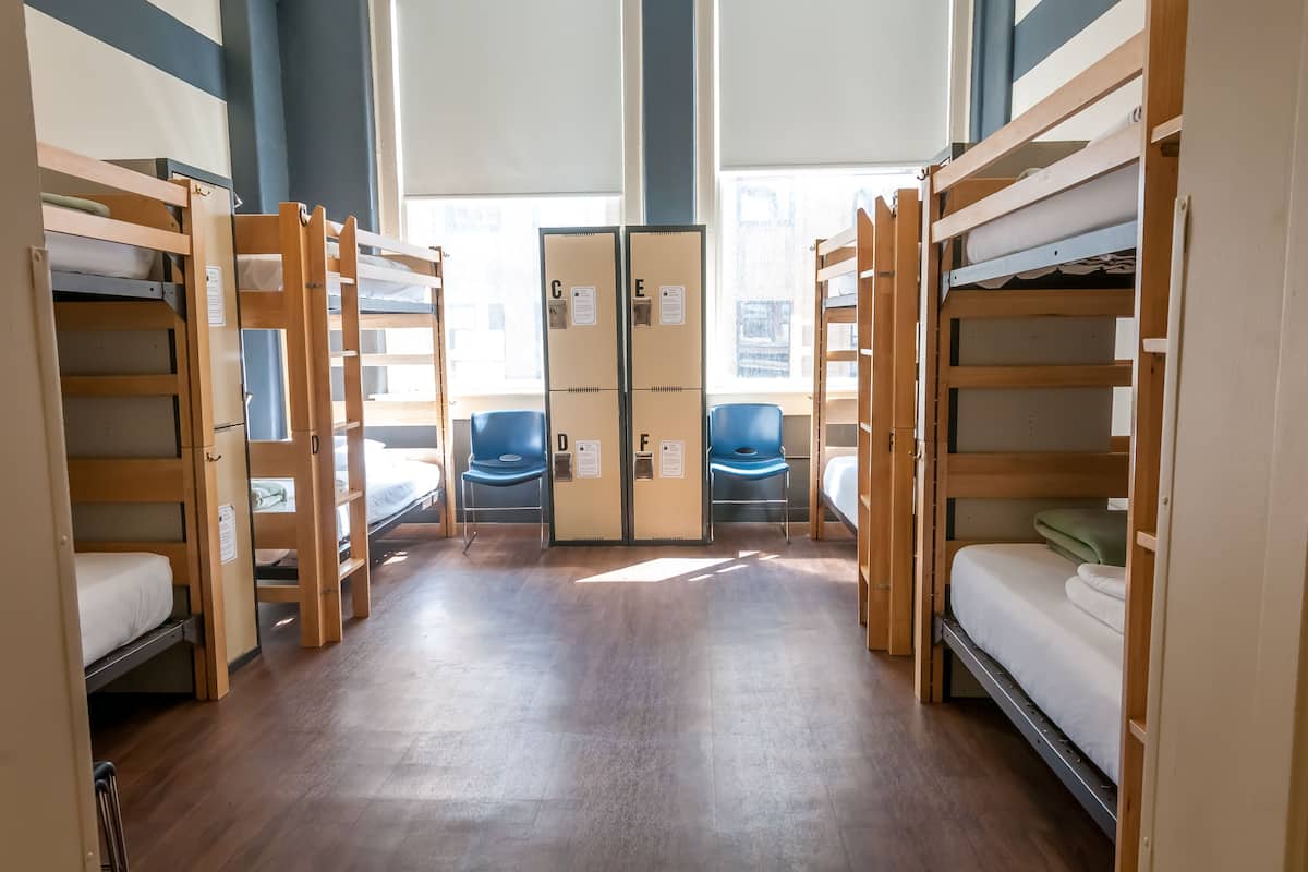 A dormitory room with bunk beds, a desk, and a chair.