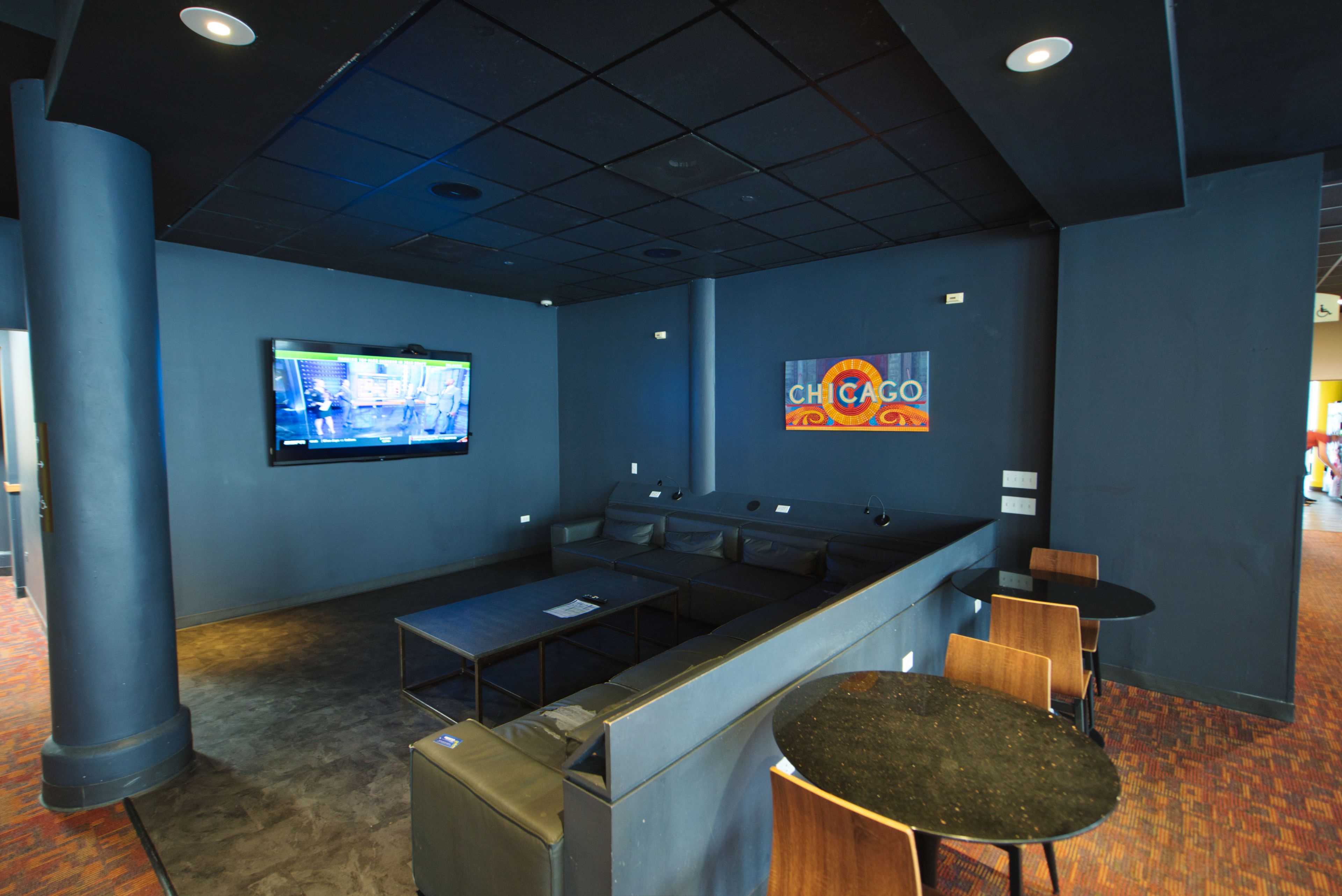 A modern bar area with a flat-screen TV, seating, and a 'CHICAGO' sign.