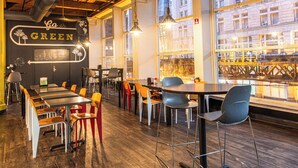 A restaurant interior with wooden floors, multiple tables and chairs, and large windows offering a view of the city. - HI Chicago Hostel (Chicago)
