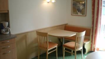 A small dining area with a table and two chairs, a coffee maker on the counter, and a painting on the wall.