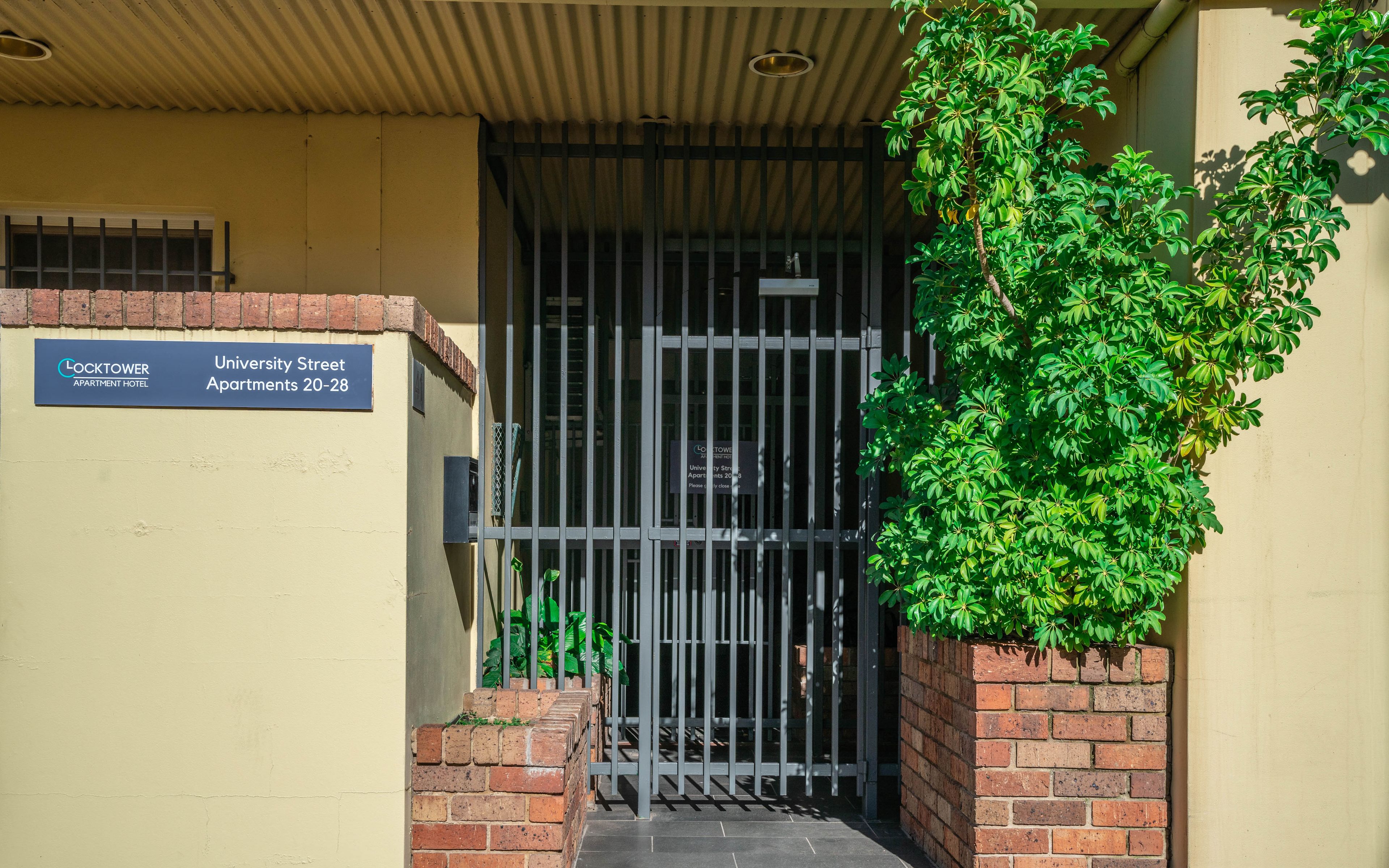 A building entrance with a sign for Lock Tower Apartments on University Street, numbers 20-28.