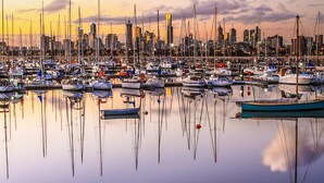 A marina with numerous boats docked, surrounded by a city skyline with modern buildings.