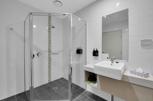 Un baño moderno con cabina de ducha de vidrio, un lavamanos blanco y un espejo encima.