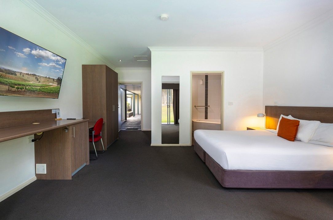 Una habitación de hotel con cama, escritorio, silla y televisor.