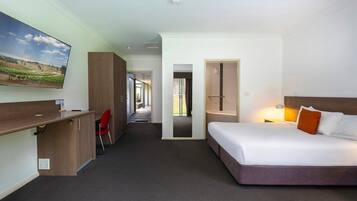 Una habitación de hotel con cama, escritorio, silla y televisor.