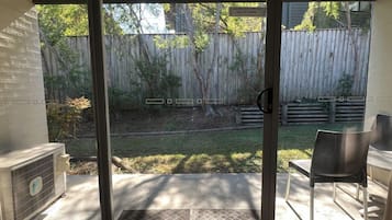 A patio area with a sliding glass door, a concrete floor, and a wooden fence in the background.