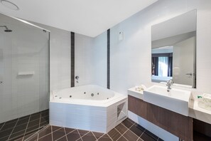 A modern bathroom with a large bathtub, a separate shower area, and a vanity with a mirror. - Hunter Gateway Motel (Rutherford)