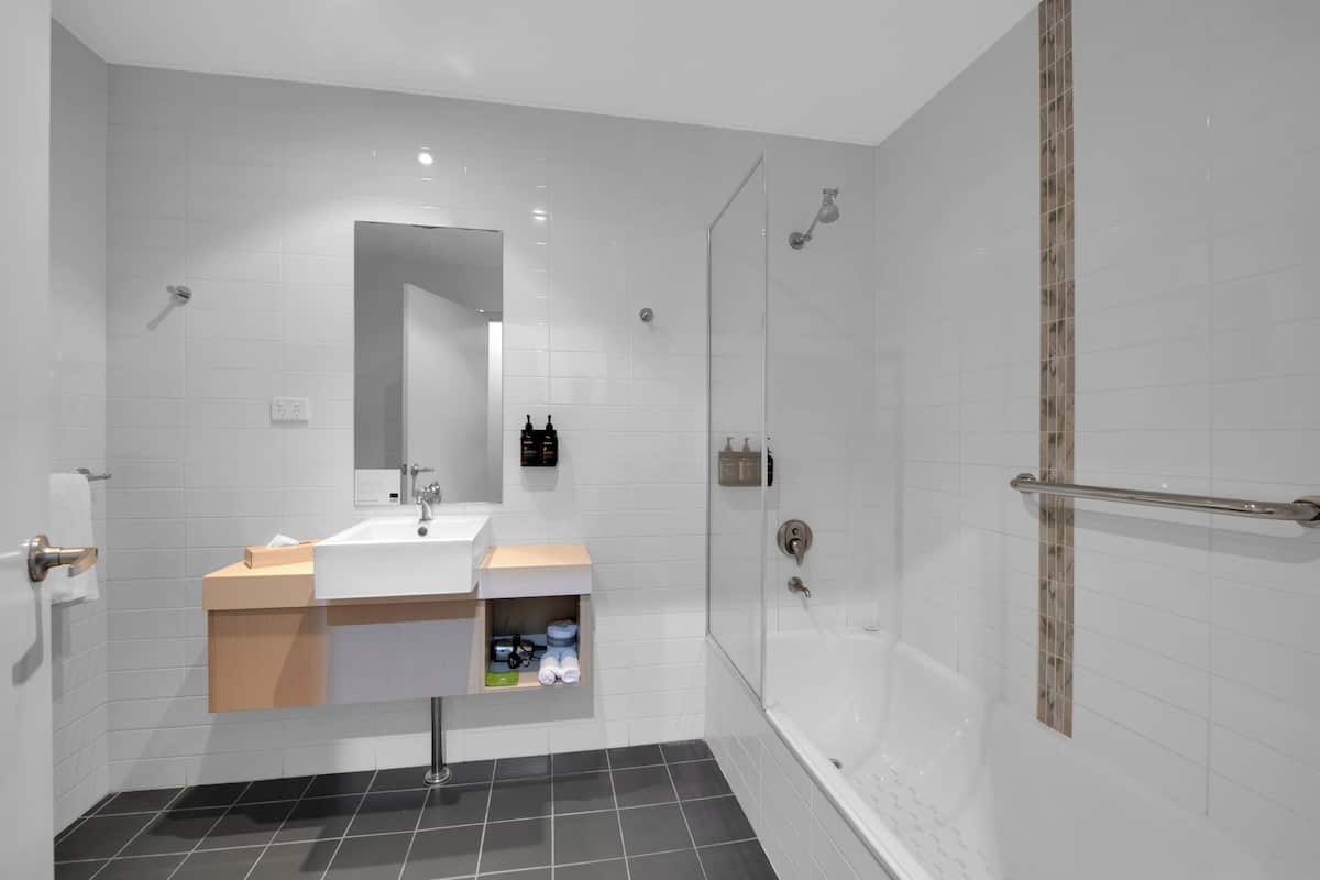 A modern bathroom with a white sink, mirror, and shower.
