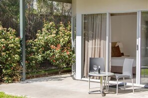 A modern hotel room with a glass door leading to a balcony, a small table with a chair, and a bed with a pillow. - Hunter Gateway Motel (Rutherford)