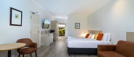 A hotel room with a bed, a desk, a chair, and a television.