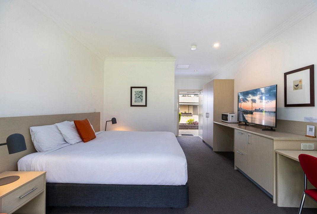 A hotel room with a bed, desk, and a view of the outside.