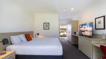 A hotel room with a bed, desk, and a view of the outside.