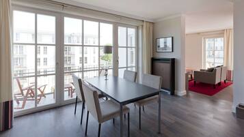 A spacious room with a large dining table, comfortable seating, a fireplace, and large windows offering a view of the city.