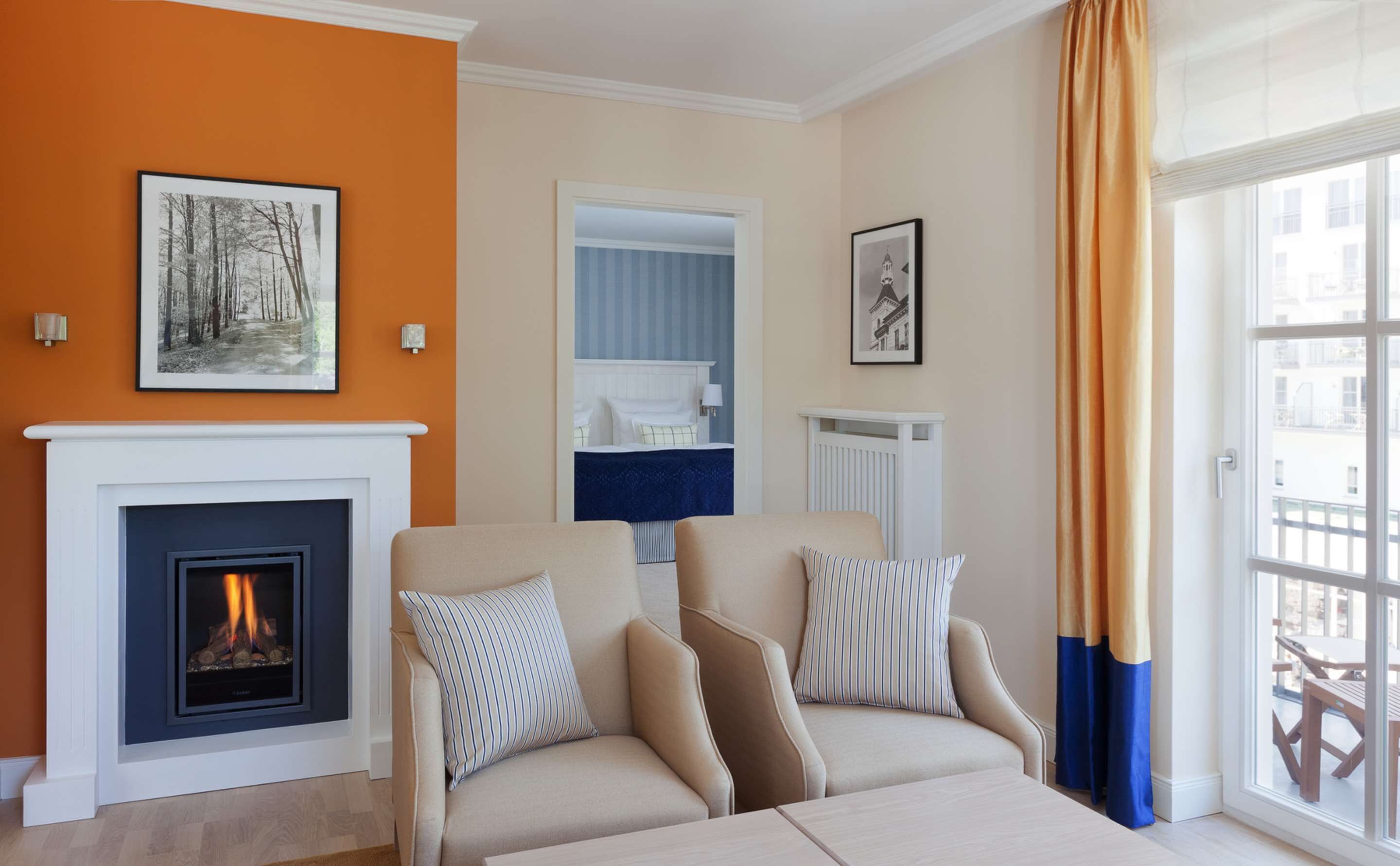 A living room with a fireplace, a sofa set, and a view of the outside.