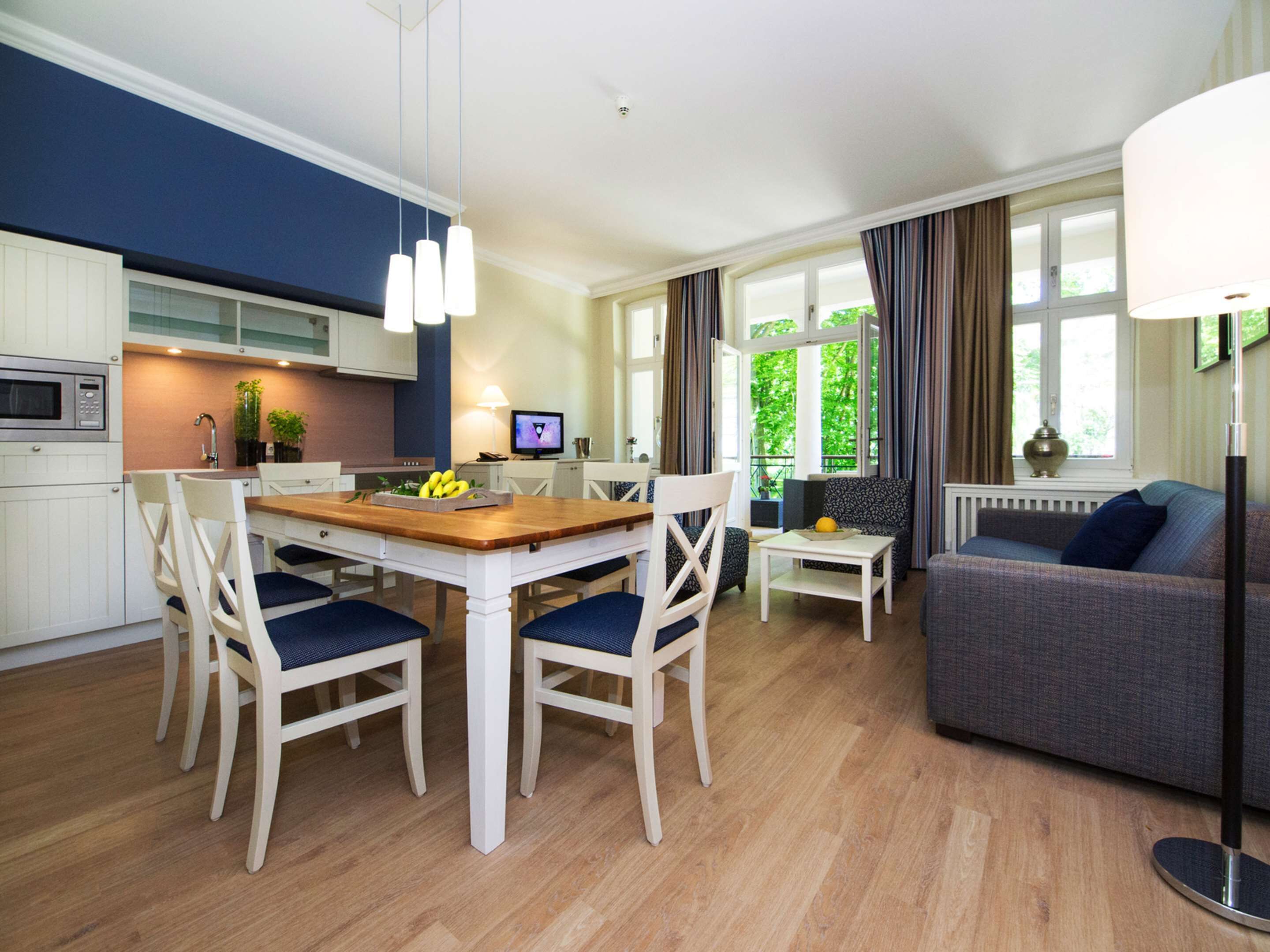A modern kitchen with white cabinets, a wooden dining table, and blue chairs.