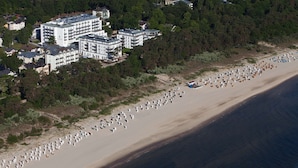 Vista aérea de una zona costera con una playa extensa y un complejo hotelero con varias construcciones.