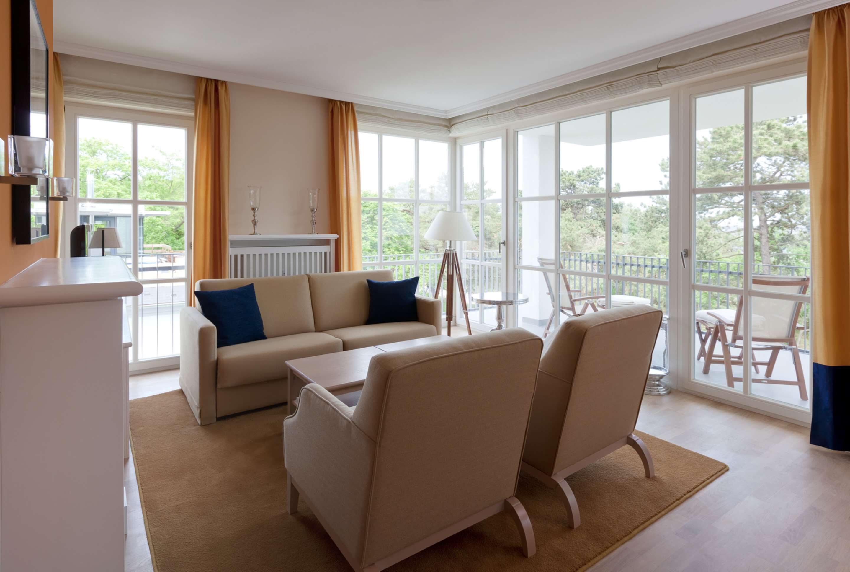 Un salón amplio con sofá, sillones, una mesa de centro y vistas al exterior a través de amplios ventanales.