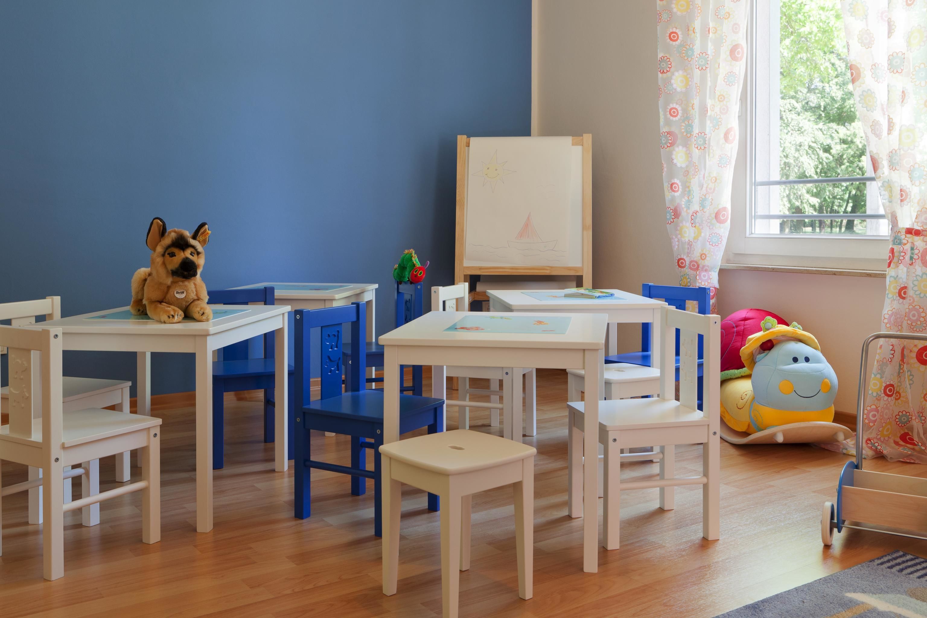 Ein Kinderspielzimmer mit Holzbeschaffenheit, einer Tafel und einem Fenster mit Vorhängen.