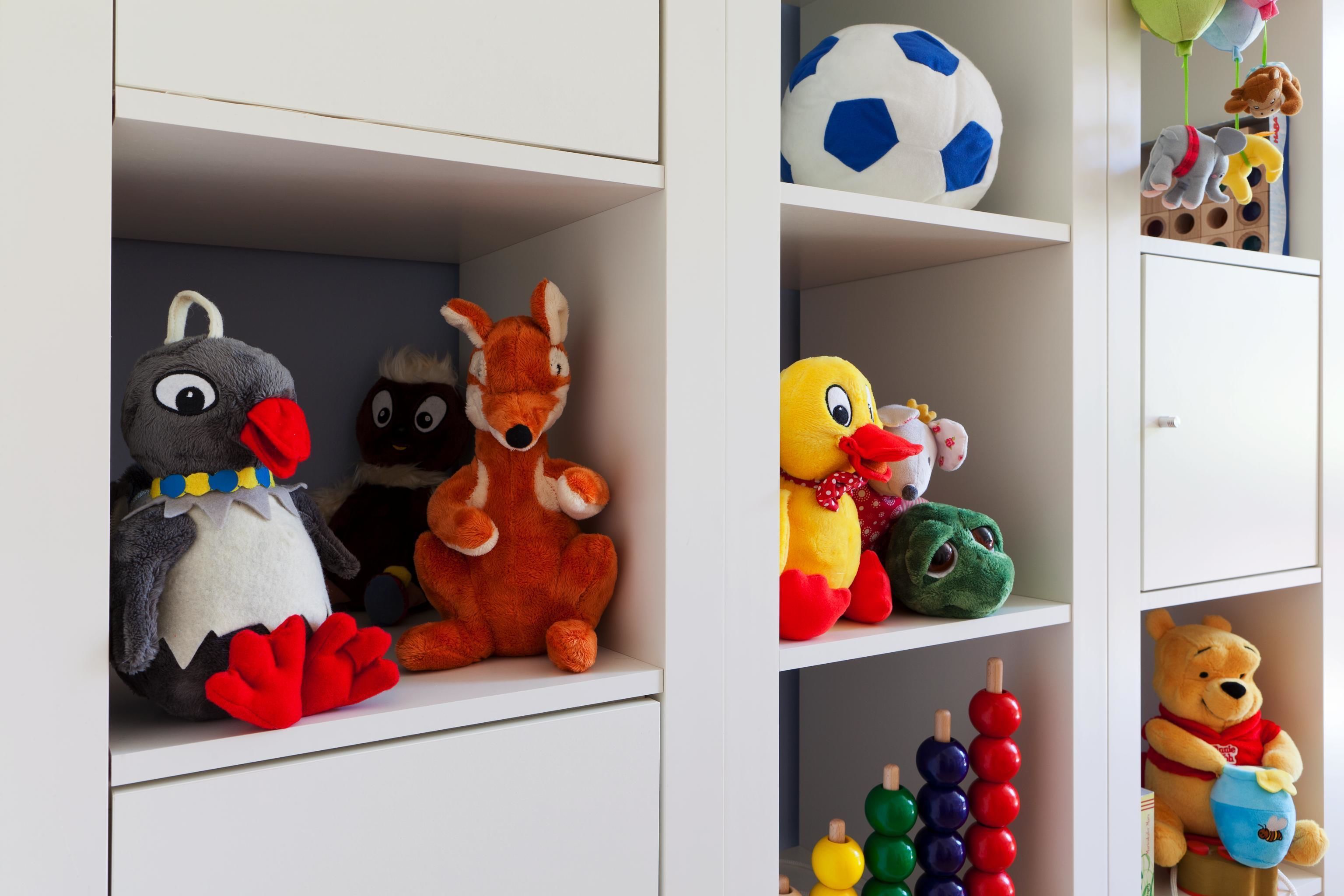Una estantería con varios peluches y un balón de fútbol.