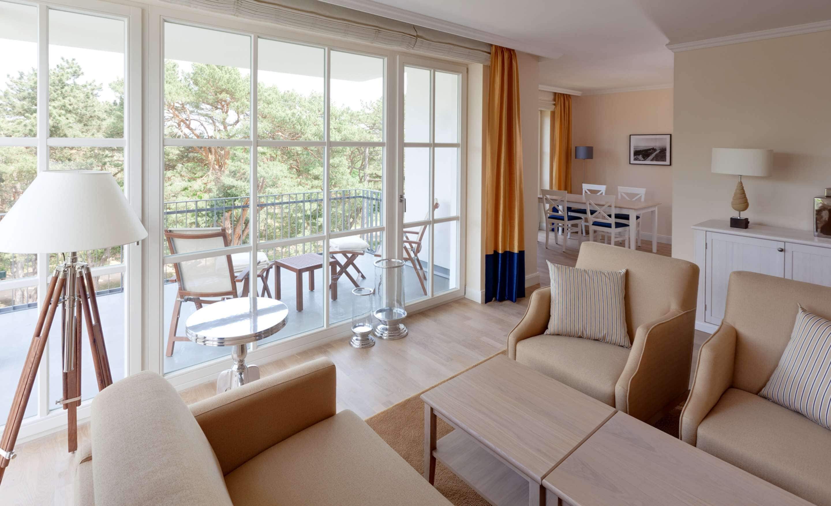 Ein geräumiges Wohnzimmer mit großen Fenstern, einem Balkon und einem Essbereich.
