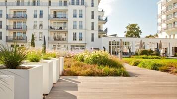 A modern apartment building with balconies, a wooden boardwalk, and landscaped gardens.