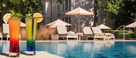 Una piscina techada, una piscina al aire libre, sombrillas