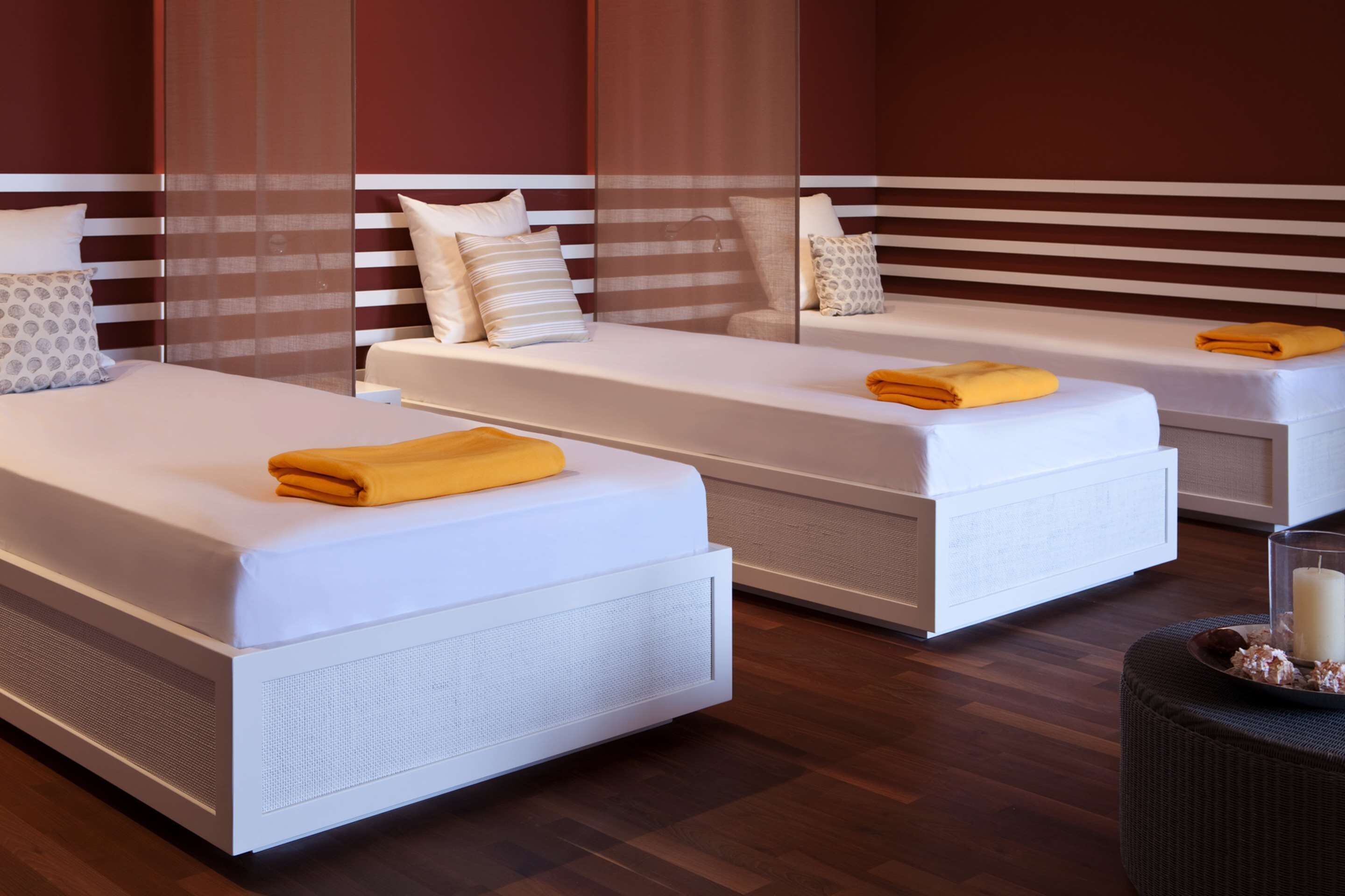Una habitación de hotel moderna con dos camas individuales, cada una con un colchón blanco y una toalla amarilla.