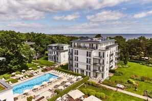 A modern multi-story hotel with a swimming pool, sun loungers, and a well-maintained garden. - Steigenberger Grandhotel & Spa (Heringsdorf)