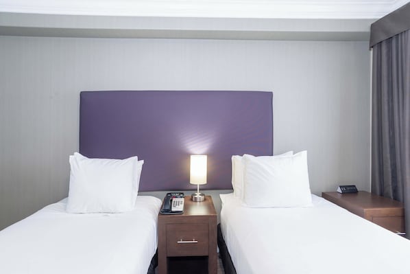 Une chambre d’hôtel avec deux lits, une table de chevet avec une lampe et un téléphone.