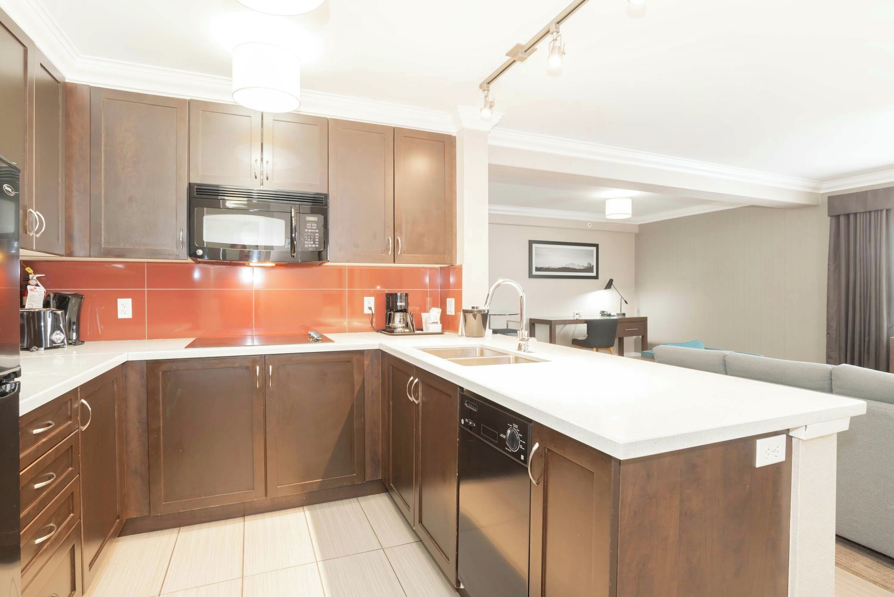 A modern kitchen with wooden cabinets, a built-in microwave, and a large island with a sink.