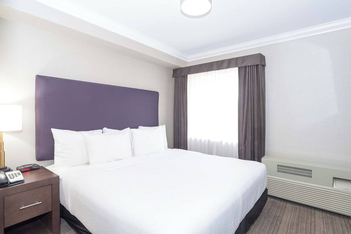 Ein Hotelzimmer mit einem großen Bett, einem Nachttisch mit Telefon und einem Heizgerät.