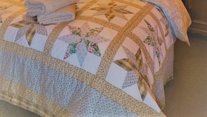 Un dormitorio con paneles de madera, una cama, dos mesitas de noche, un espejo y una colcha acolchada.