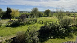 Paisaje rural con un área cercada, árboles y cielo despejado.