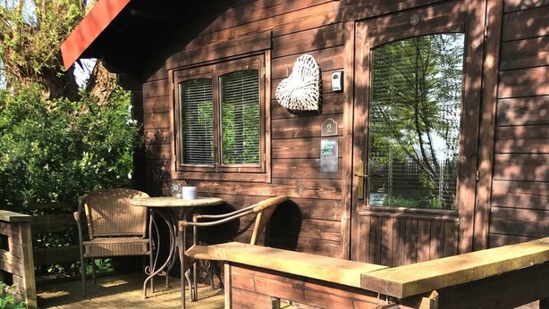 Una cabaña de madera con un porche, una mesa y sillas.