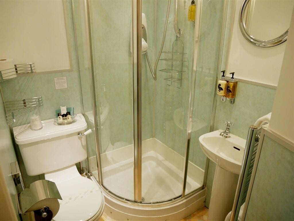 A bathroom with a glass-enclosed shower, a toilet, a sink, and a mirror.