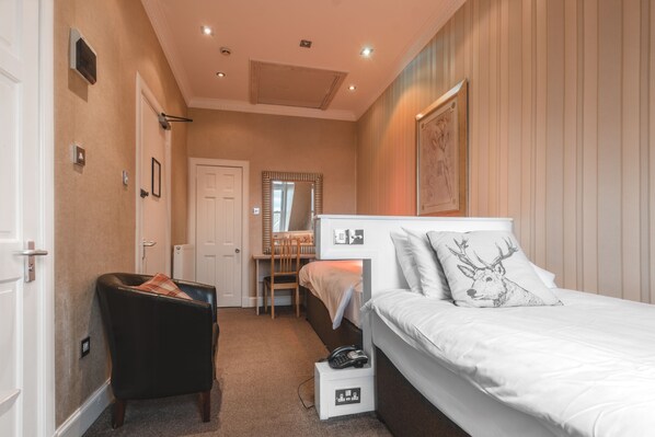 A bedroom with a bed, a chair, a desk, and a mirror.