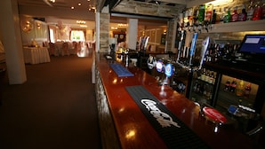 A bar area with a polished wooden counter, a Coca-Cola branded coaster, and a variety of liquor bottles. - Grange Moor Hotel (Maidstone)