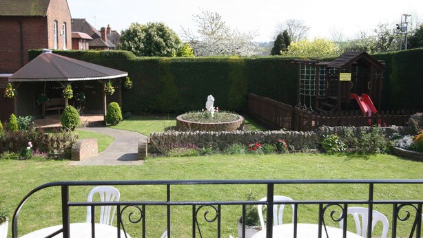A garden with a gazebo, a fountain, and a red slide. - Grange Moor Hotel (Maidstone)