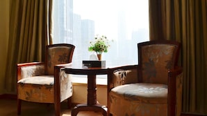 A room with two upholstered chairs, a small table, and a vase with flowers. - Vili International Hotel (Guangzhou)