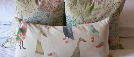 A bed with a green blanket and floral patterned pillows.