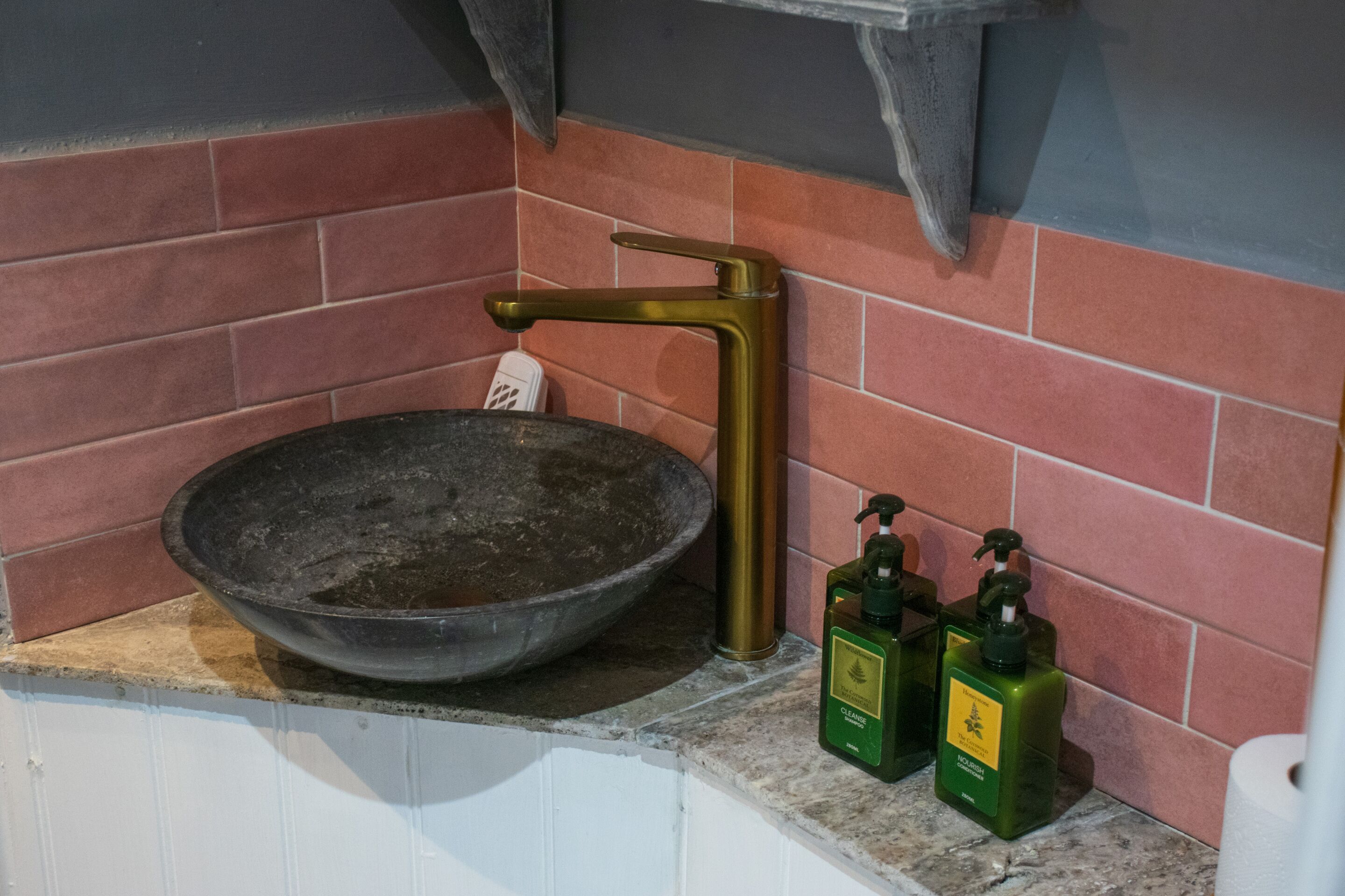 Un baño con un lavamanos grande, un perchero y dos botellas de jabón.