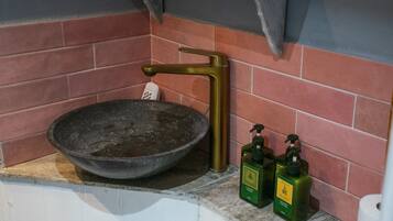Un baño con un lavamanos grande, un perchero y dos botellas de jabón.