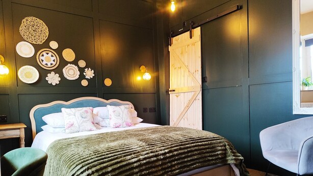 A bedroom with a bed, a chair, a wooden door, and wall decorations.