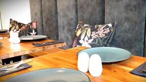 A dining table with plates, cutlery, and floral-patterned cushions.
