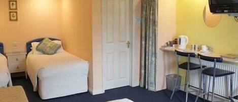 A hotel room with a bed, a desk with a chair, a television, and a door.