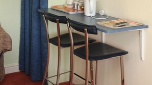A small kitchenette with a table, two bar stools, a coffee maker, a kettle, and a microwave. - Little Bullocks Farm (Bishop's Stortford)