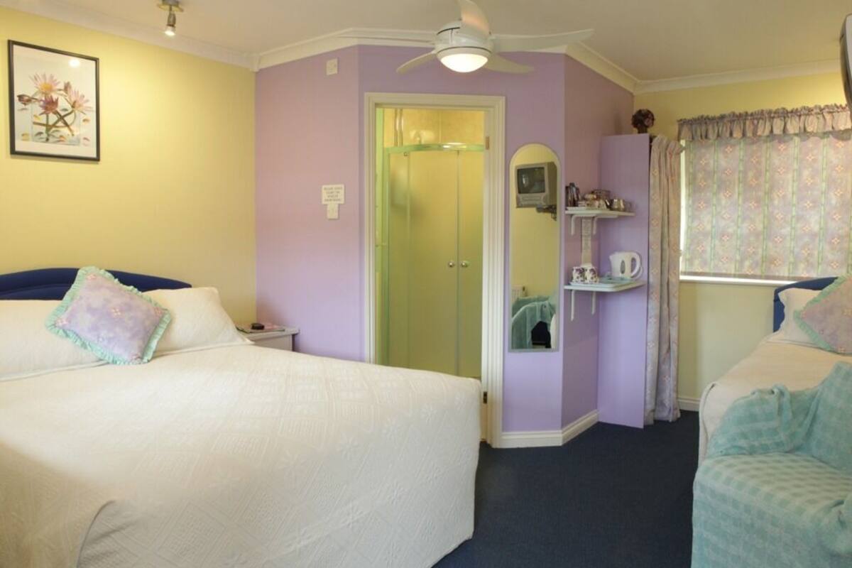 Ein Schlafzimmer mit zwei Betten, einem Deckenventilator, einer Dusche und einem Schminktisch mit Spiegel.
