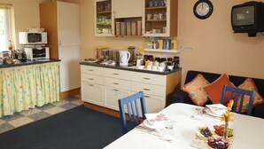 A compact kitchen with a dining area, featuring a microwave, kettle, and various kitchen utensils. - Little Bullocks Farm (Bishop's Stortford)