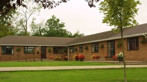 A two-story brick building with a flat roof, multiple windows, and a covered front porch. - Little Bullocks Farm (Bishop's Stortford)